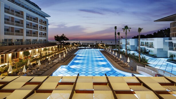 Um hotel com uma piscina grande, várias varandas e áreas de estar ao ar livre.