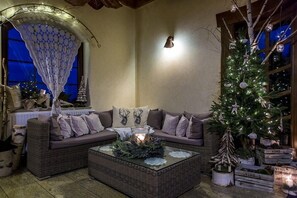 Una sala de estar acogedora con un sofá modular, una mesa de centro de vidrio, un árbol de Navidad y un dosel decorativo.