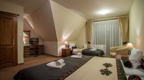 Habitación de hotel con dos camas, un escritorio con computadora, una silla y un ventanal con cortinas.