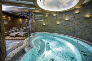 Un área de spa con hidromasaje, paredes de madera, detalles de piedra y un techo decorado con un diseño de nubes.