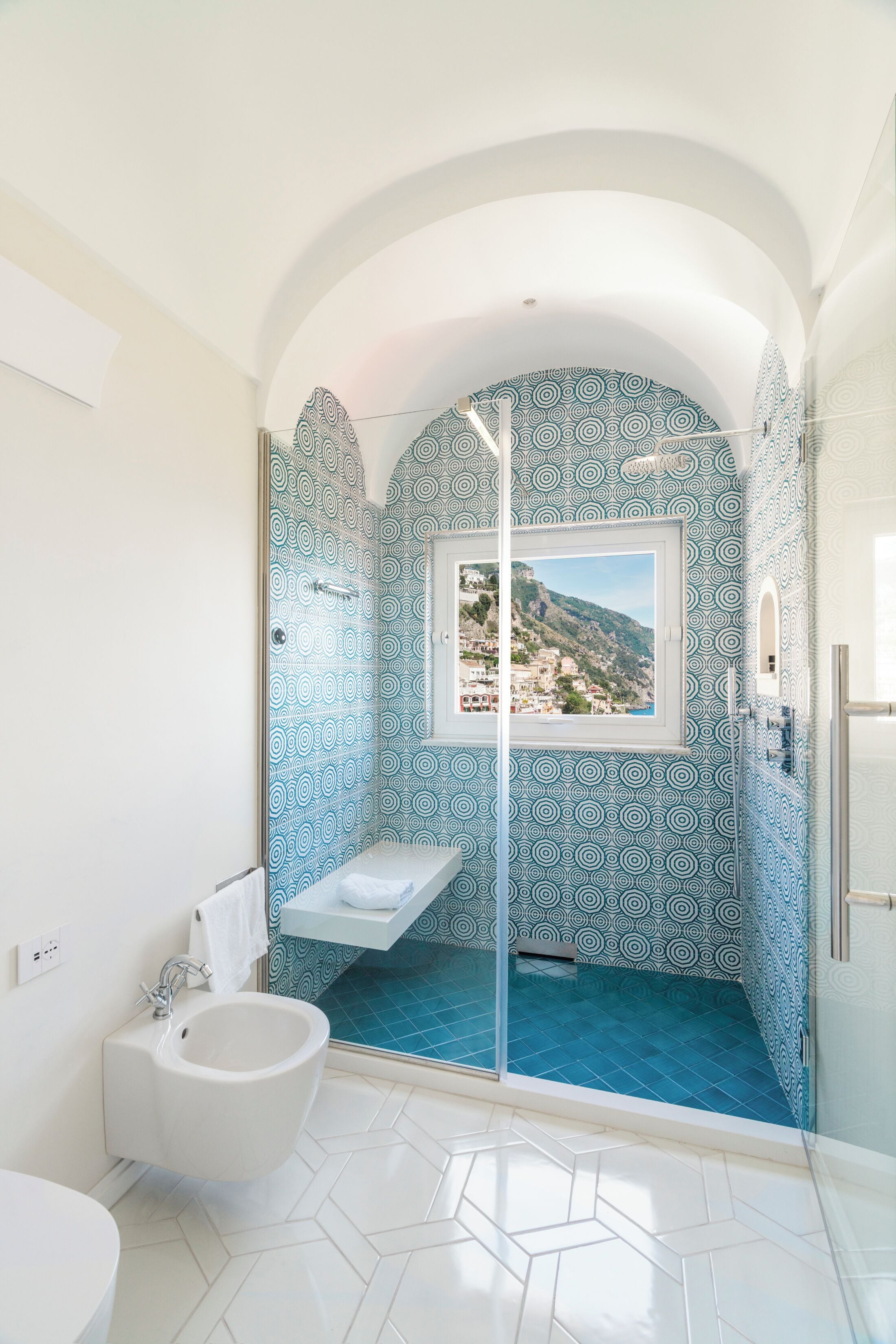 Une salle de bain avec douche, un bidet et une fenêtre donnant sur une colline.