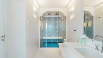 A modern bathroom with a glass-enclosed shower, a white sink, and a large mirror.