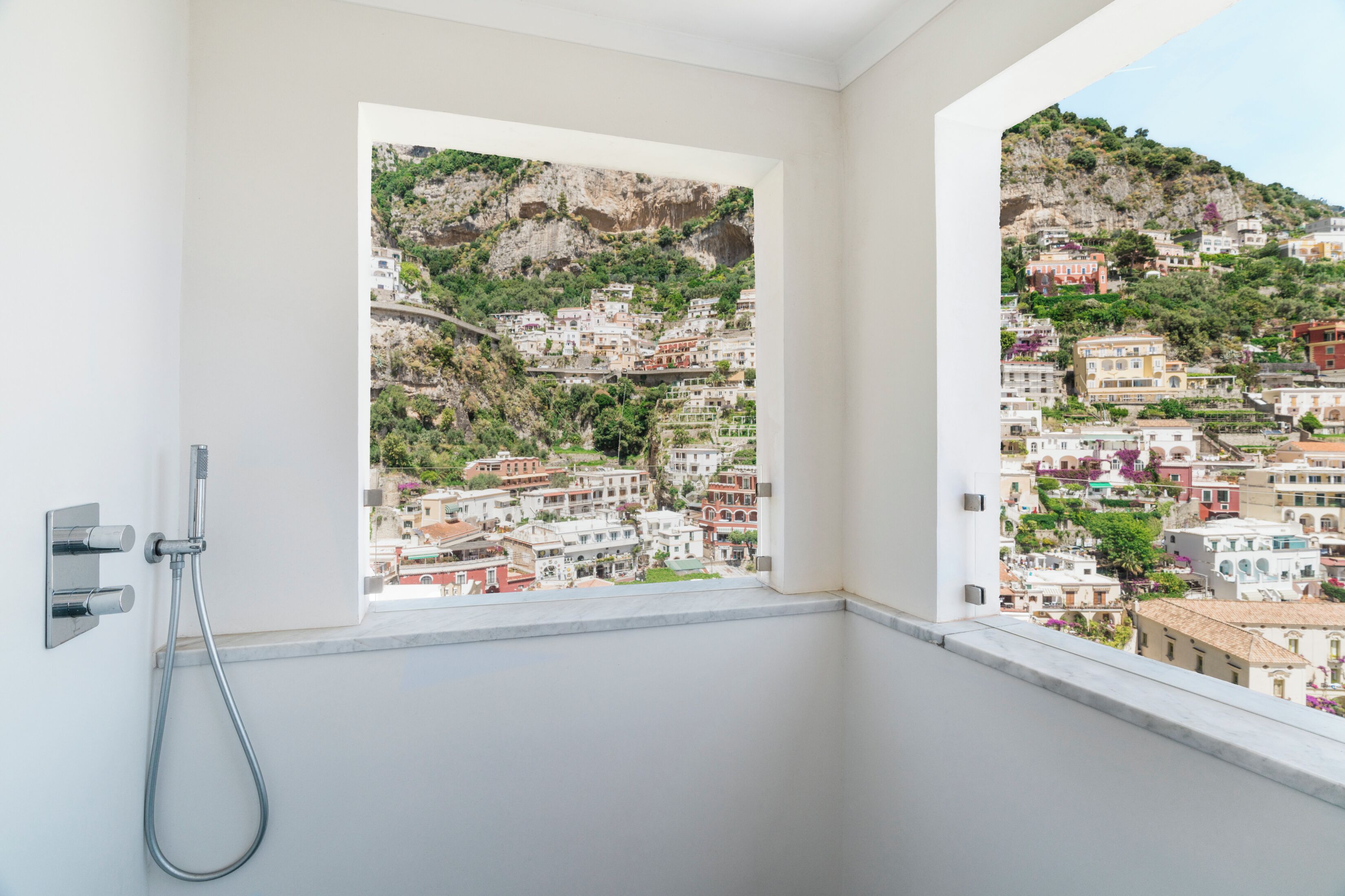 Un baño con ducha y vistas a un pueblo en la ladera.