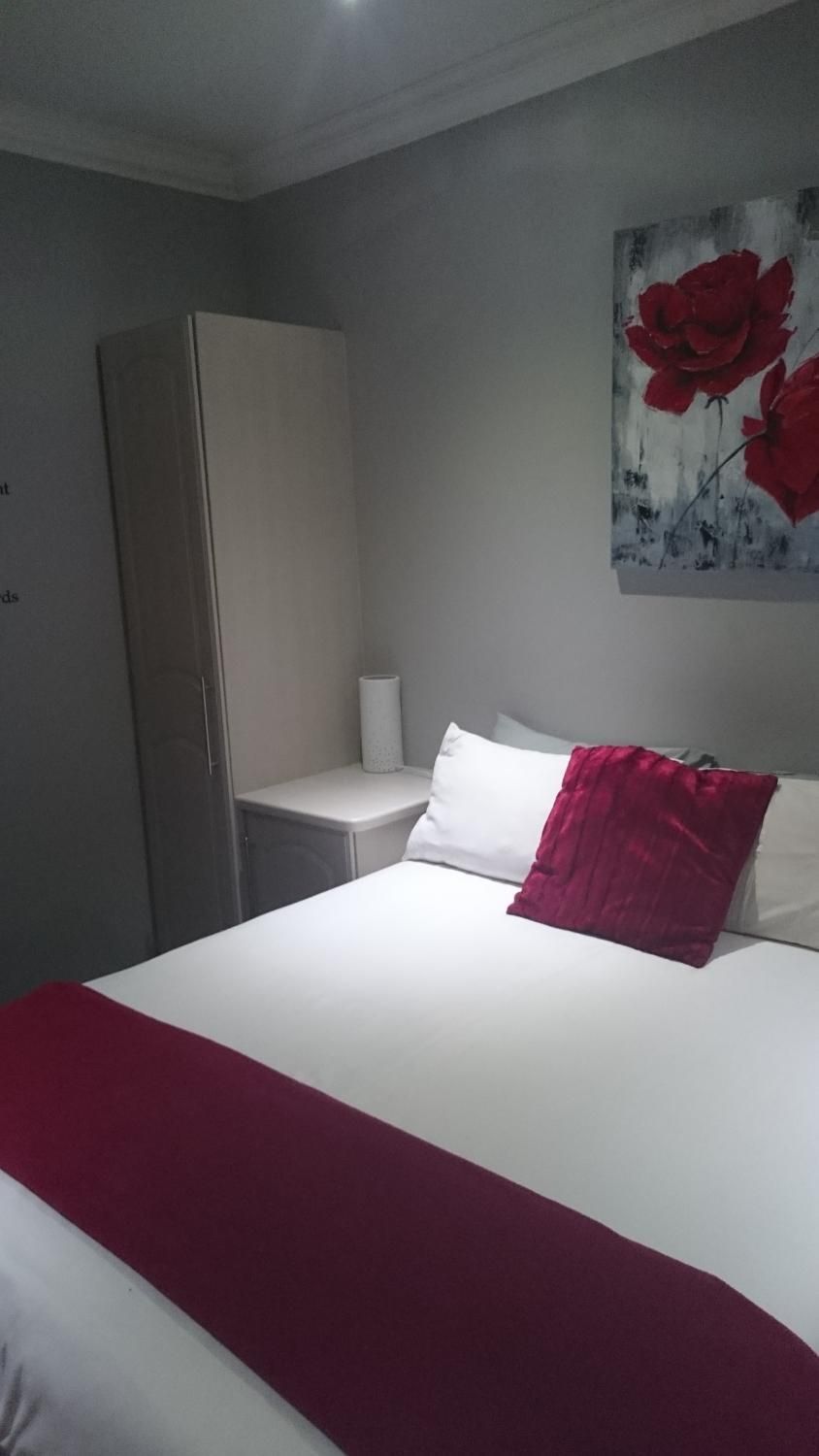 A hotel room with a bed, a nightstand, a wardrobe, and a painting on the wall.