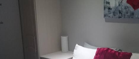 A bedroom with a bed, a wardrobe, and a painting on the wall.