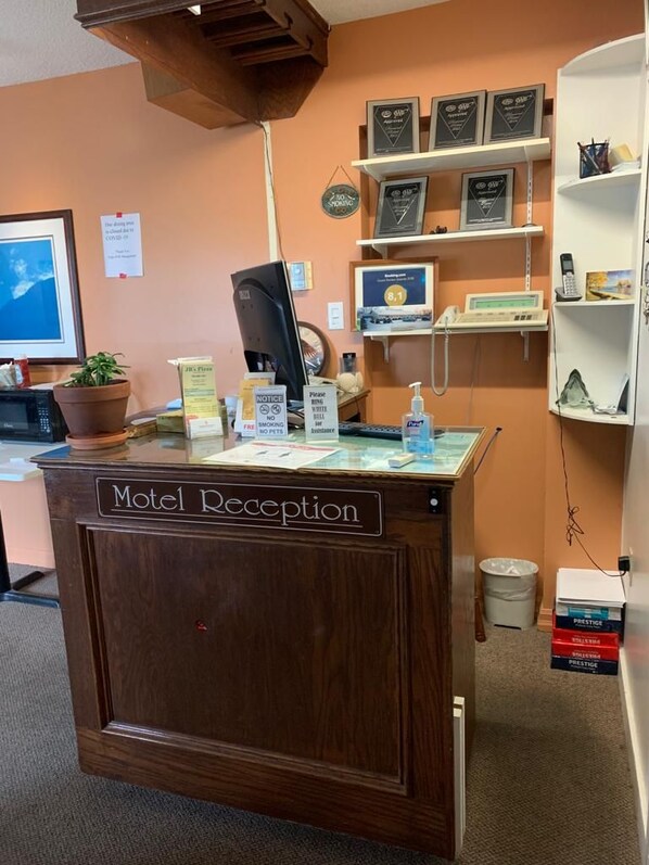 A motel reception desk with a computer, a telephone, and a sign indicating a 10% discount. - Auberge Eldo Inn (Blind River)