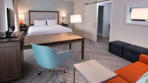 A hotel room with a bed, desk, chair, and seating area. - Chateau Fredericton, Trademark Collection by Wyndham (Fredericton)