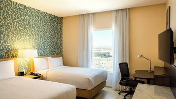 Une chambre d’hôtel avec deux lits, un bureau, une chaise, une télévision et une fenêtre donnant sur un beau paysage.