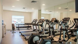 Un gimnasio con cintas de correr, elípticas y mancuernas.