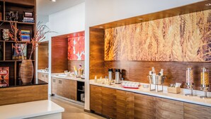 Una cocina moderna con armarios de madera, encimera blanca y diversos electrodomésticos.