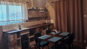 A compact kitchen with a built-in sink, a dining area with a table and chairs, and a hanging light fixture.