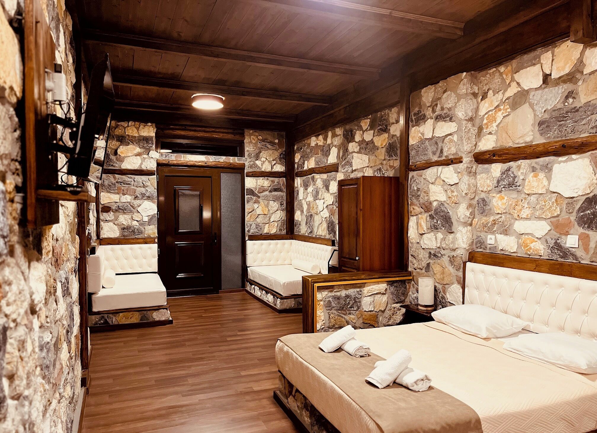 A room with stone walls, wooden beams, and a bed with white linens.