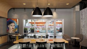 Un espace de salle à manger moderne avec une longue table, des chaises noires et des luminaires suspendus.