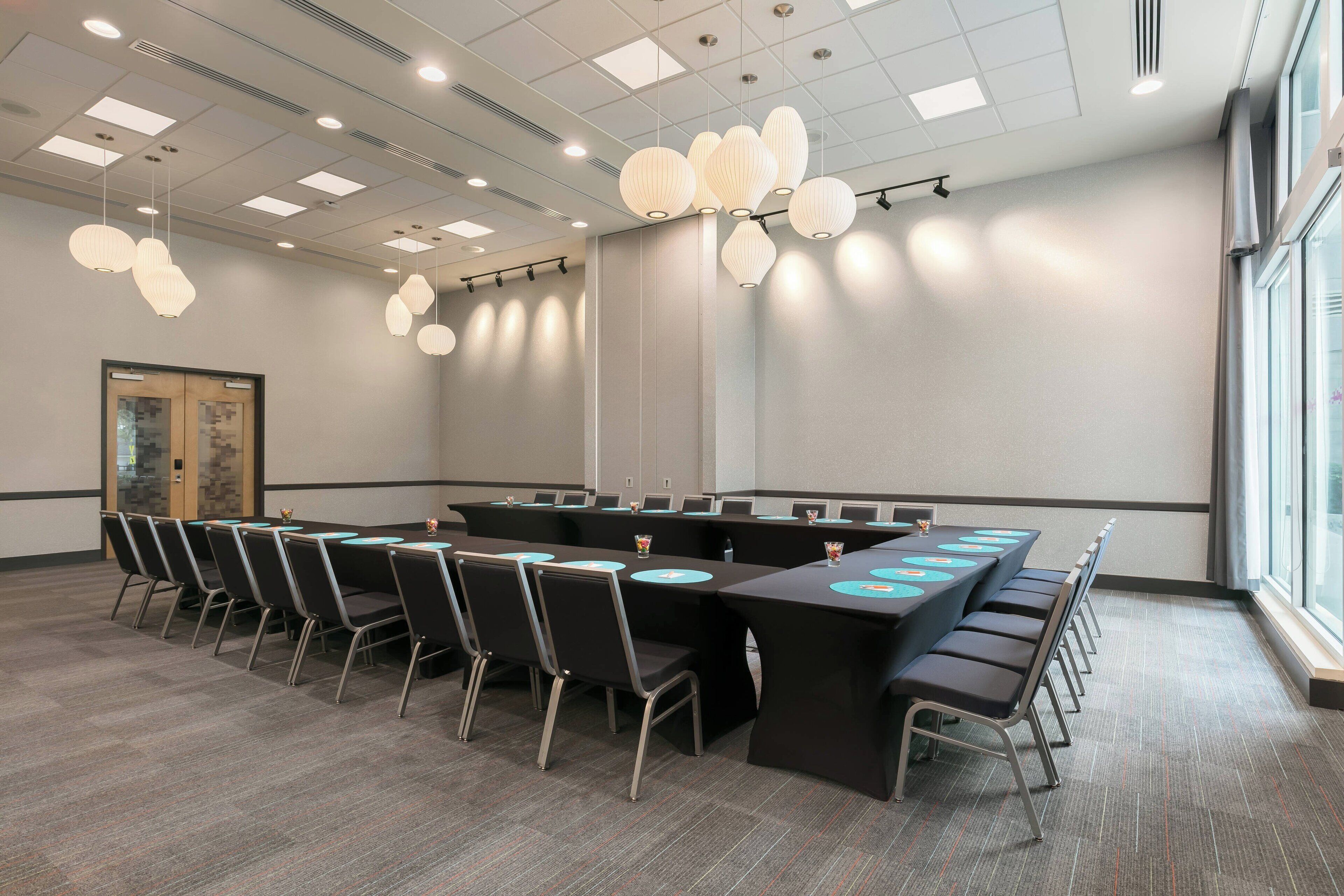 Une salle de conférence avec une longue table, des chaises et des luminaires suspendus.