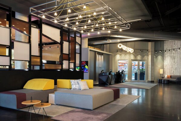 A modern lobby with a seating area, a reception desk, and a visible entrance.