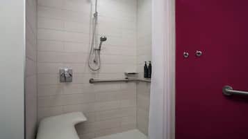A modern bathroom with a shower, toilet, and a red door.