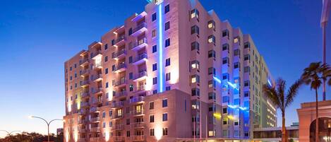 A multi-story hotel with balconies, a rooftop terrace, and a well-lit entrance.