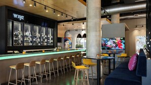 Un espace bar avec un néon, des tabourets de bar, un canapé et un écran de télévision.