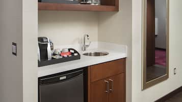 A compact kitchen with a dishwasher, a coffee maker, and a sink.