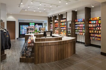 A modern coffee shop with a marble counter, black pendant lights, and a refrigerated display case. at Parkwest Bicycle Casino