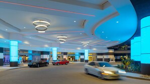 Un moderno vestíbulo de hotel con techo curvo, iluminación empotrada y una estatua en el centro.