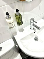 Ein Badezimmer mit einem weißen Waschbecken, zwei Flaschen Hand- und Körperlotion sowie einem Chromarmaturen.