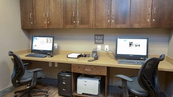 A workspace with two desks, each with a computer, office chairs, a printer, and a filing cabinet.