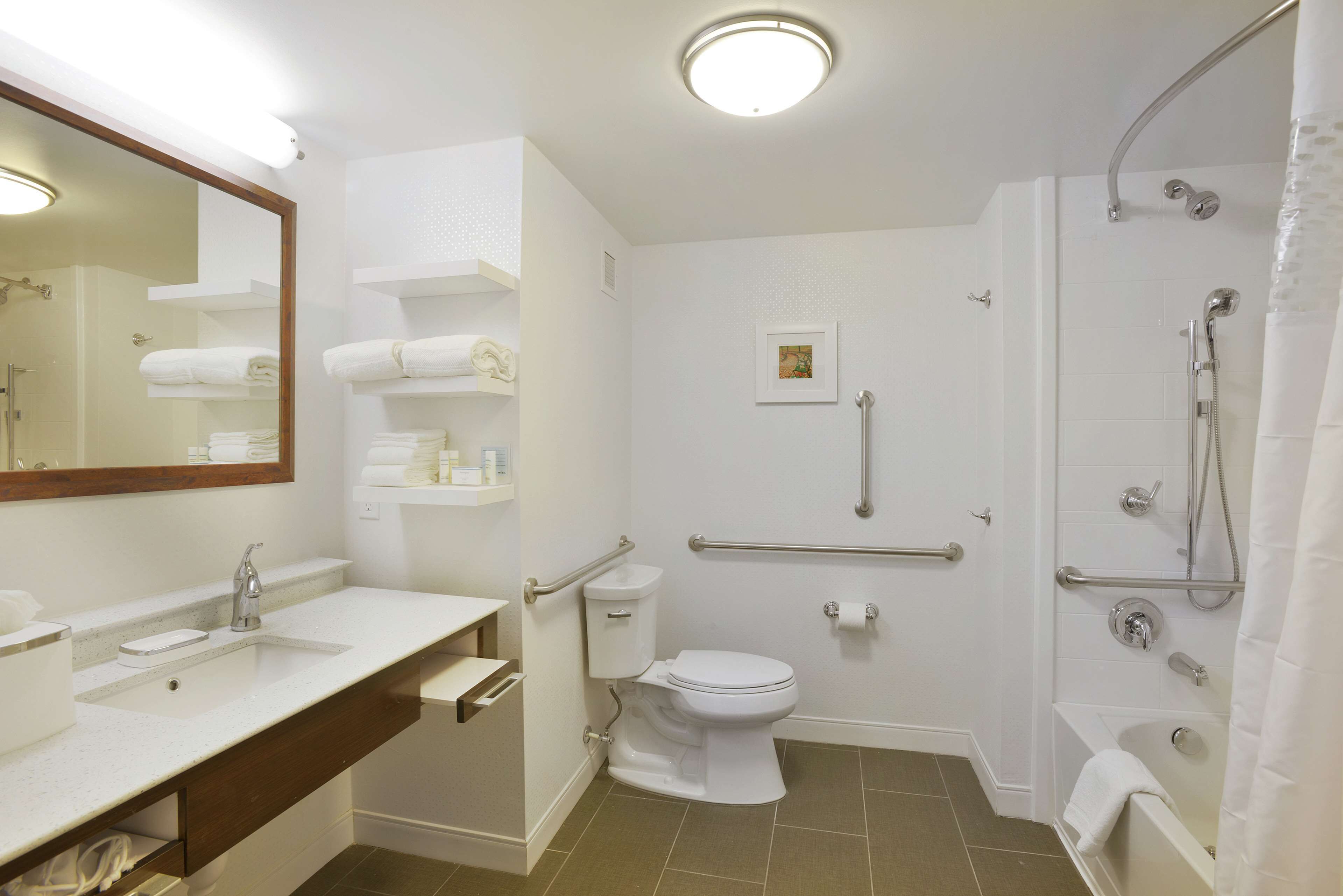A modern bathroom with a sink, toilet, shower, and a mirror.