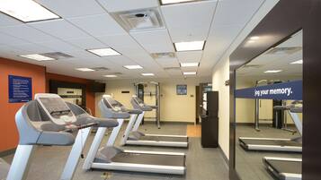 Un gimnasio con cintas de correr, un espejo grande y un letrero que dice 'Jog your memory'.