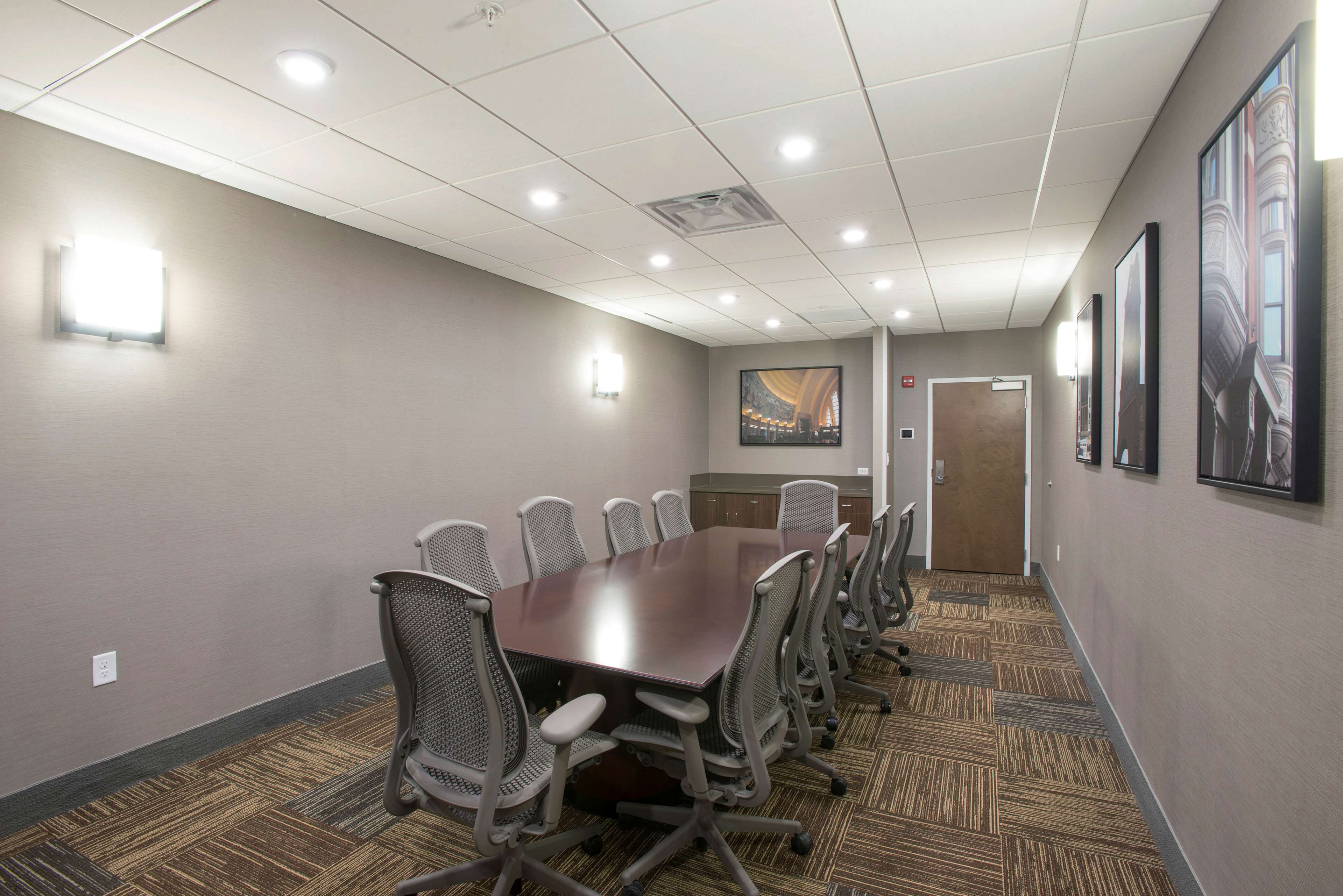 A conference room with a long table, chairs, and carpeted flooring.