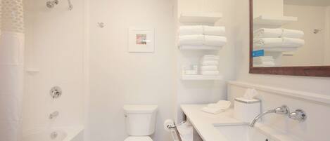 A modern bathroom with a bathtub, toilet, and a sink with a mirror.