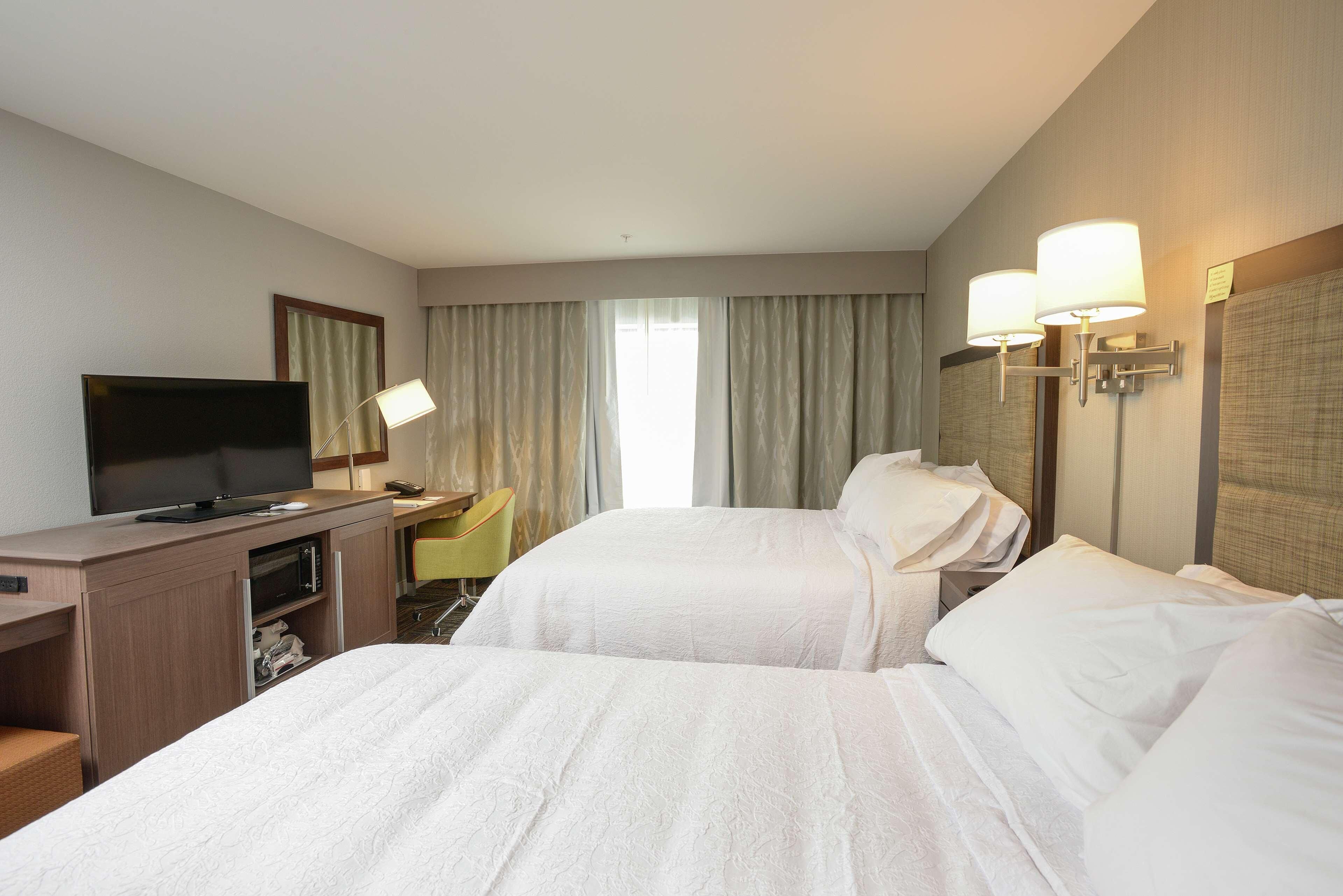 Une chambre d’hôtel avec deux lits, une télévision, un bureau et une chaise.