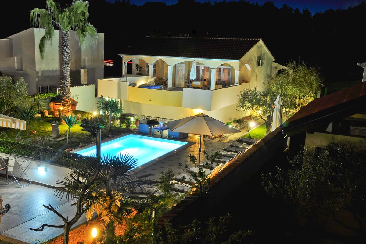 A two-story building with a swimming pool, outdoor seating, and a well-lit patio area.