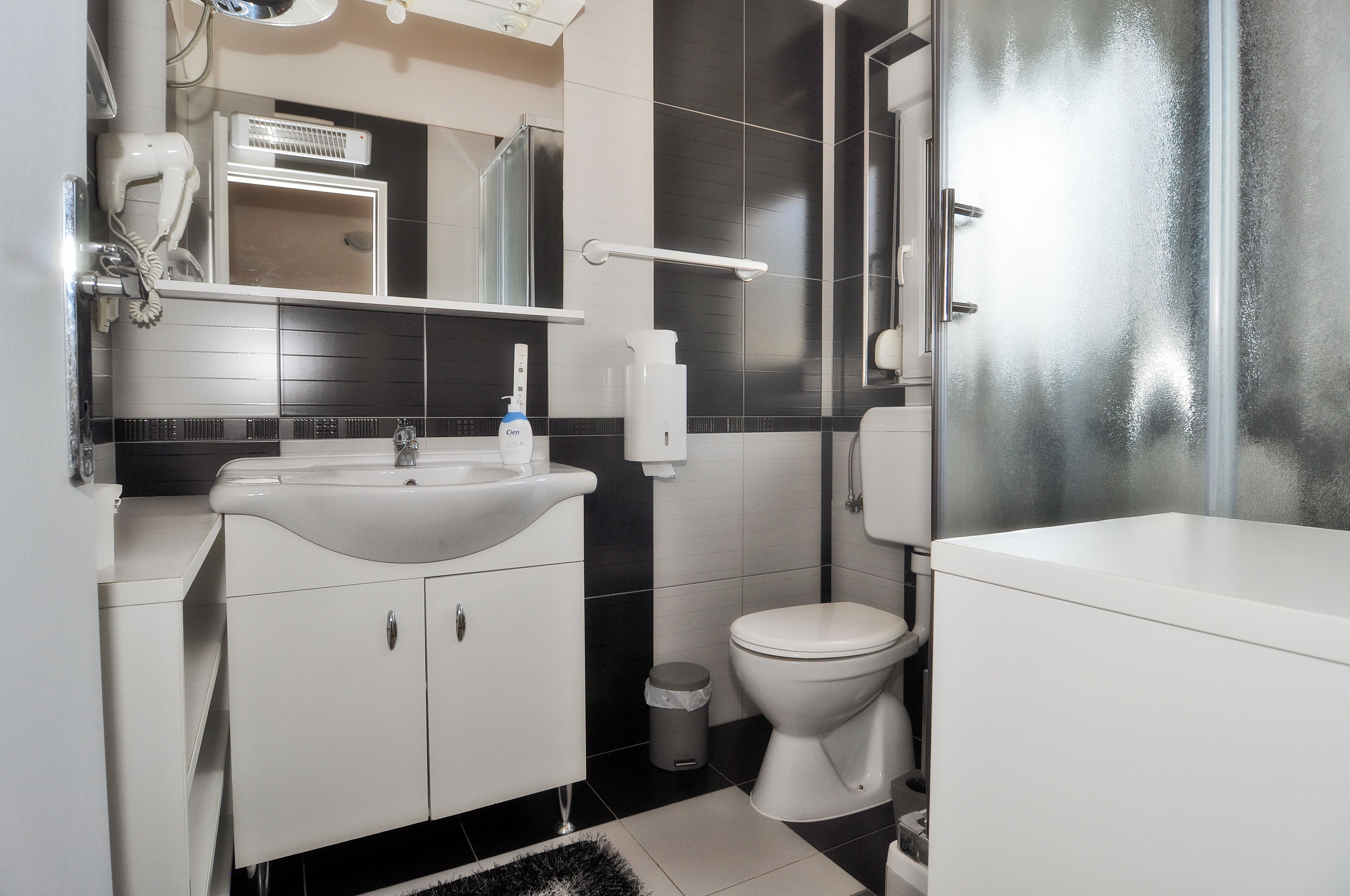 A modern bathroom with a white sink, toilet, and shower area.