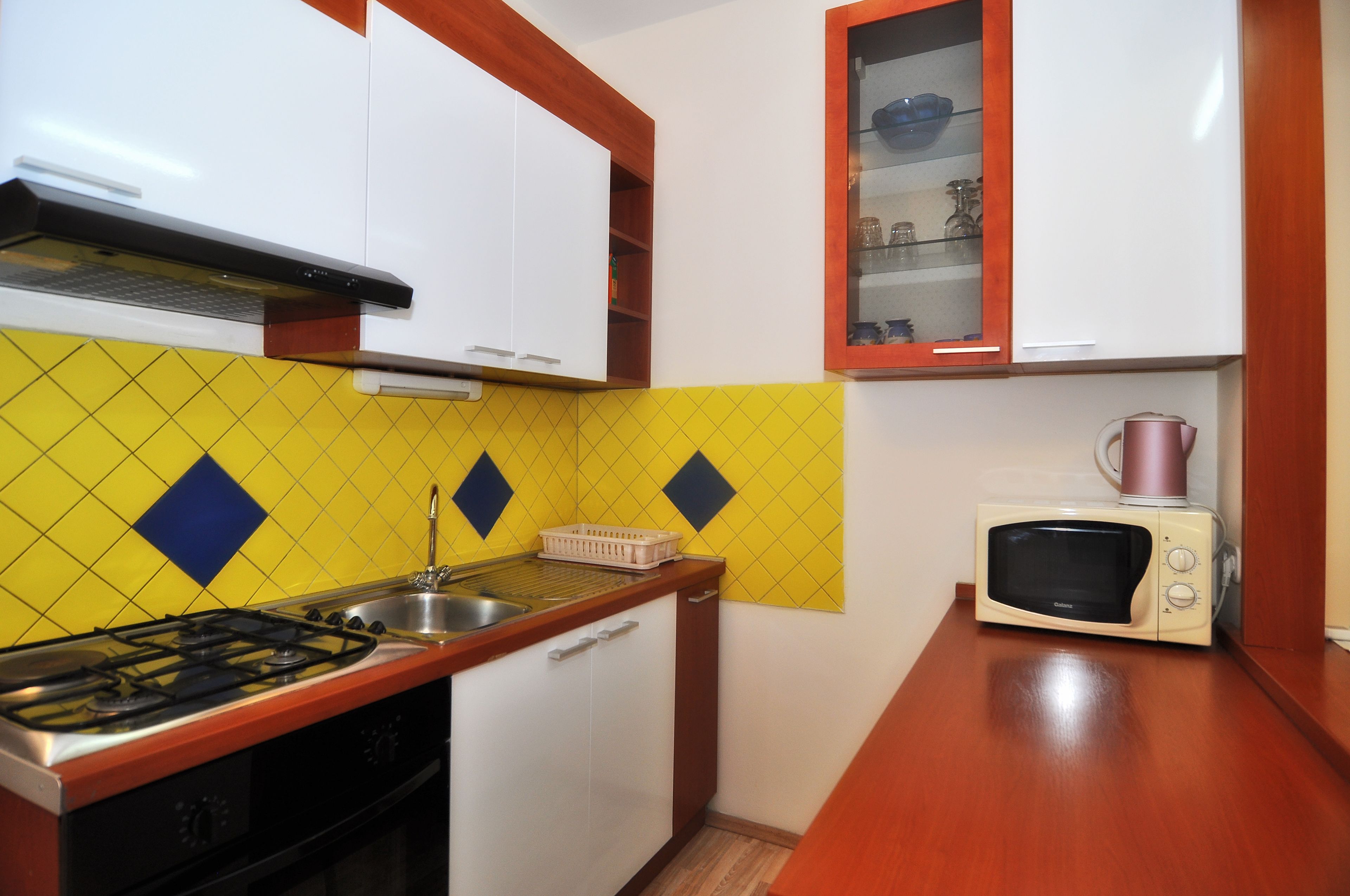 Une cuisine de taille réduite équipée d’une cuisinière à gaz, d’un évier et d’un four à micro-ondes.