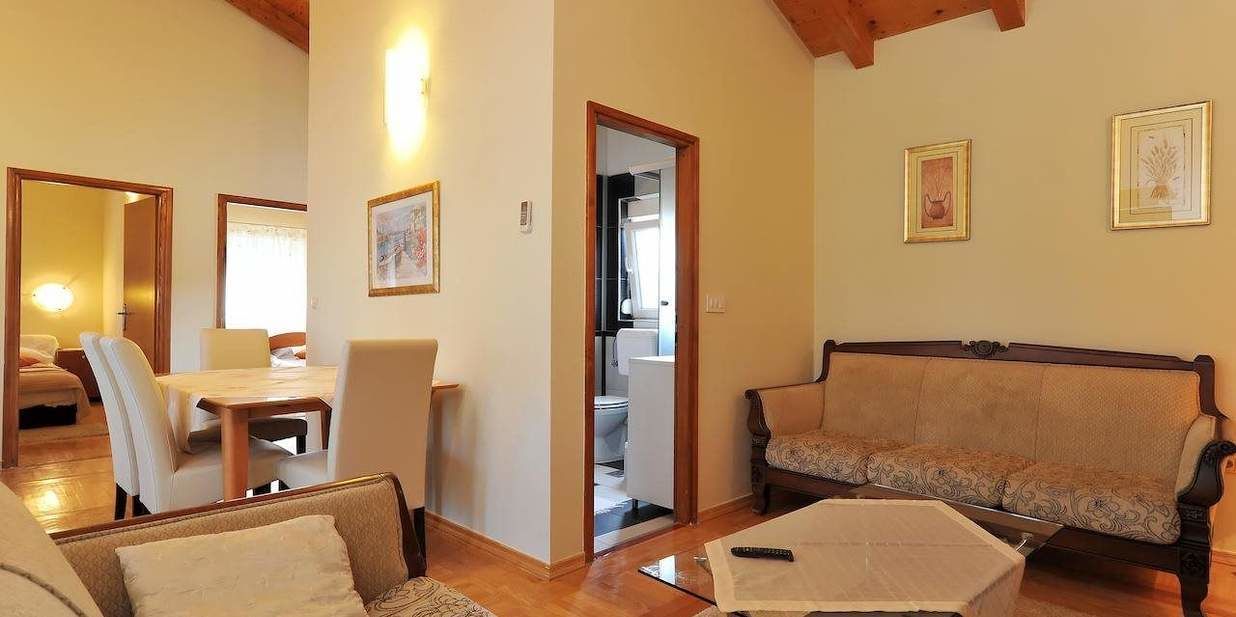 Una sala de estar acogedora con un sofá, sillas, una mesa de comedor y una cocina a la vista a través de una puerta abierta.