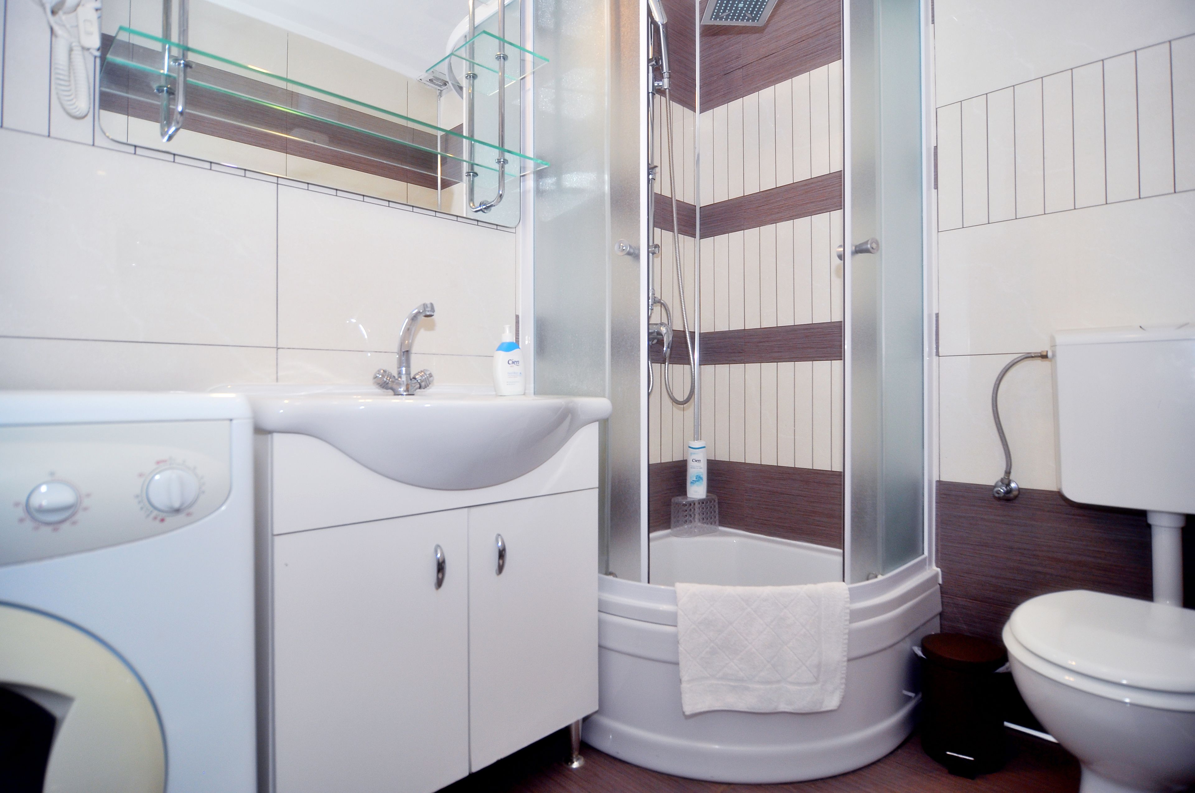 Ein Badezimmer mit Waschbecken, Spiegel, Duschkabine aus Glas und Toilette.