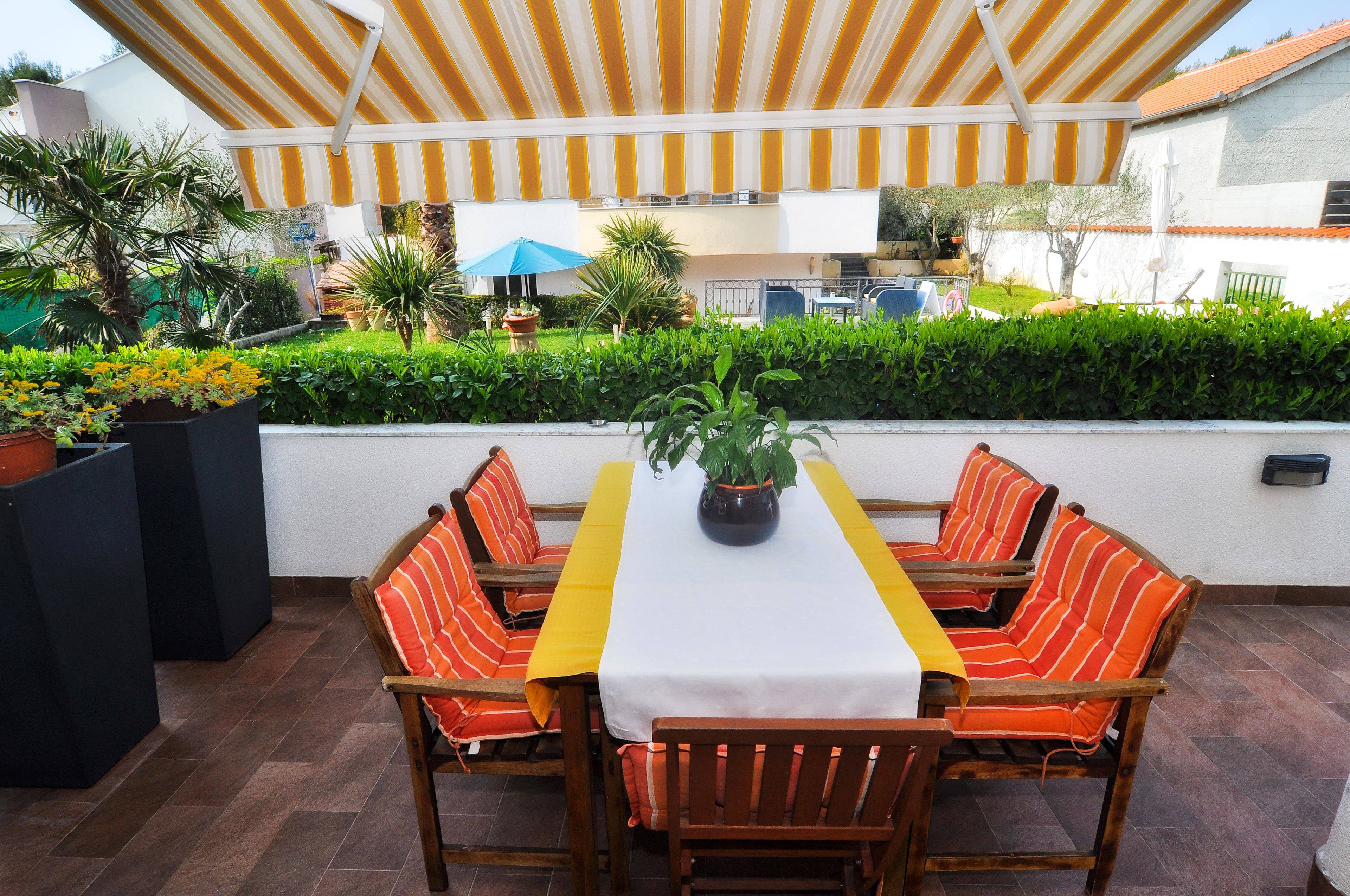 An outdoor patio with a table and chairs, surrounded by greenery and potted plants.