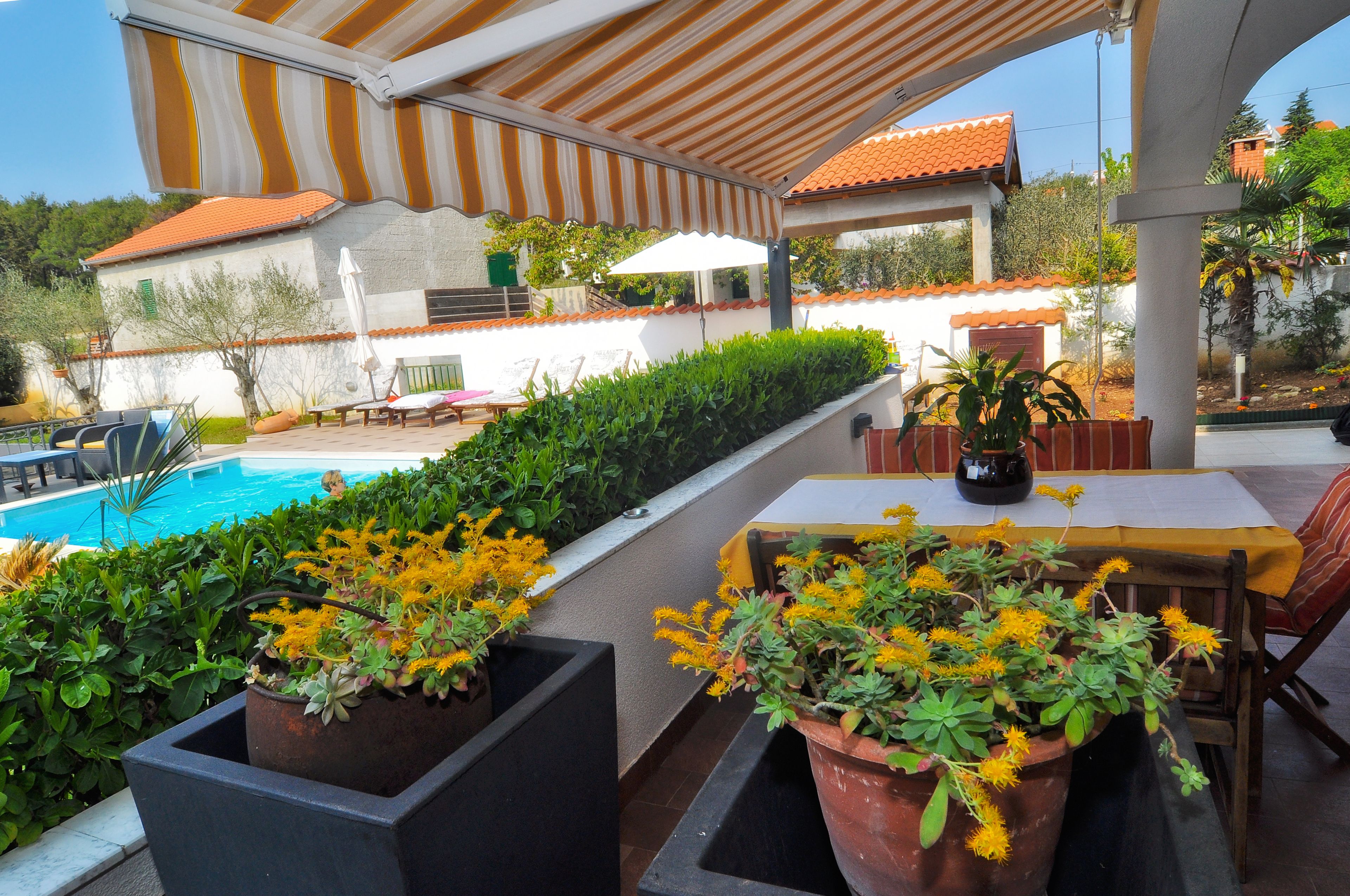 Un espacio al aire libre cubierto con piscina, plantas en macetas y una mesa con sillas.