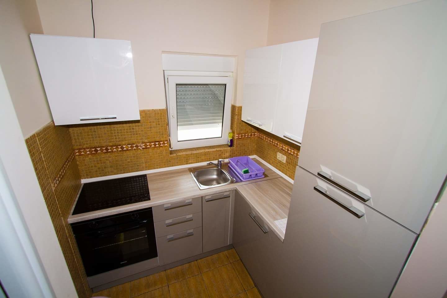 A compact kitchen with a stove, sink, and refrigerator.