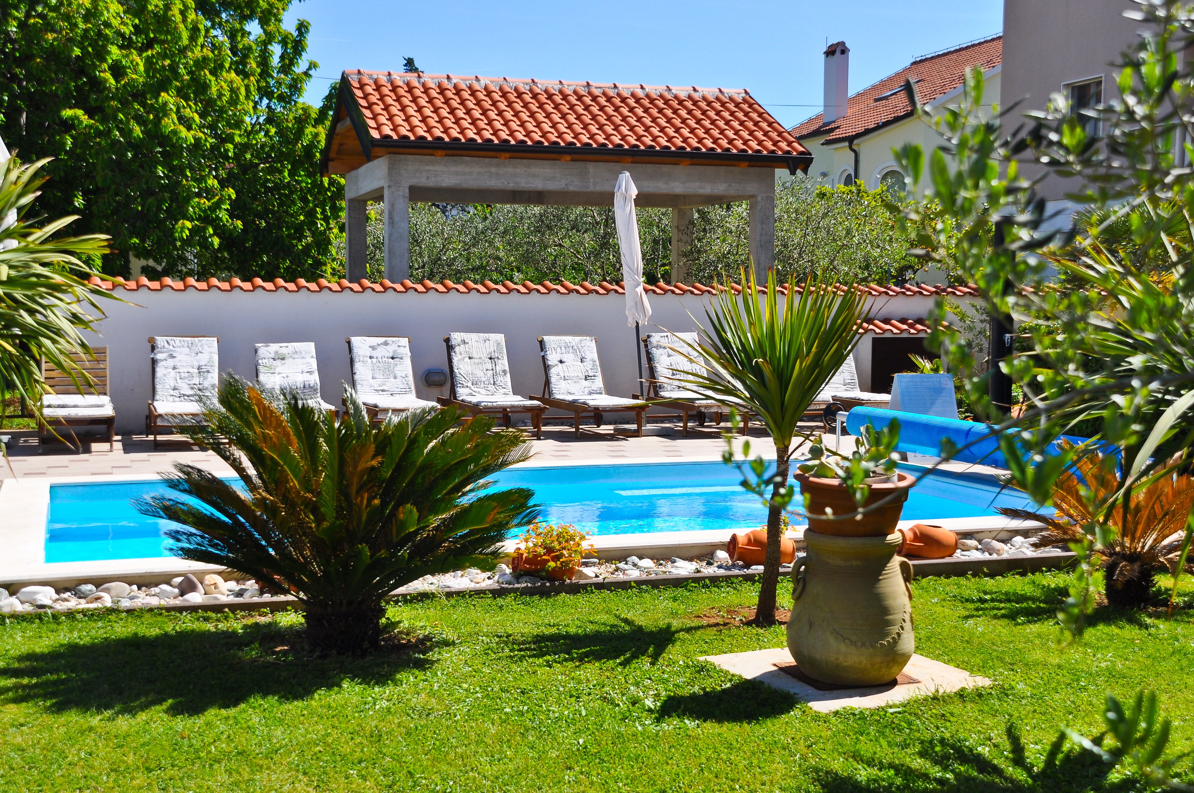 Un área de piscina con sillones de descanso y una pérgola.
