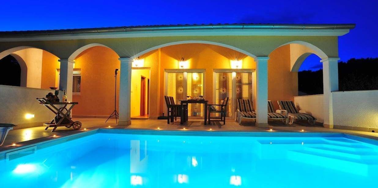 Ein Schwimmbad mit überdachtem Bereich, Liegestühlen und einem Tisch.