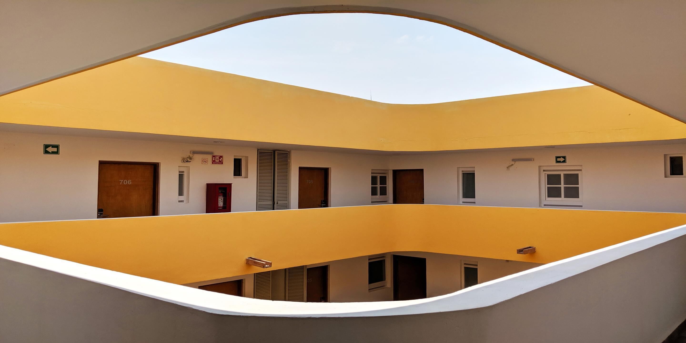 A multi-level interior with a central open space, multiple doors, and a clear view of the sky through an archway.