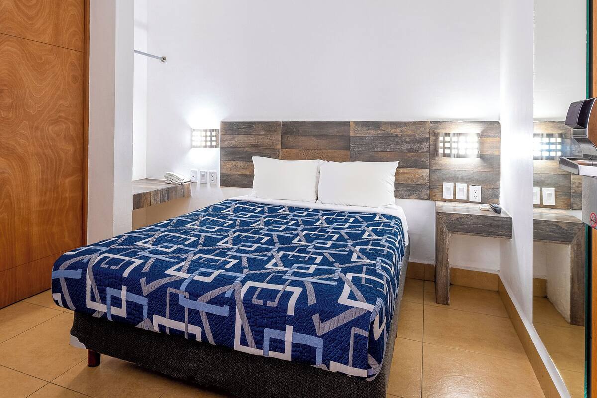 A bedroom with a bed, wooden headboard, bedside tables, and a nightstand.