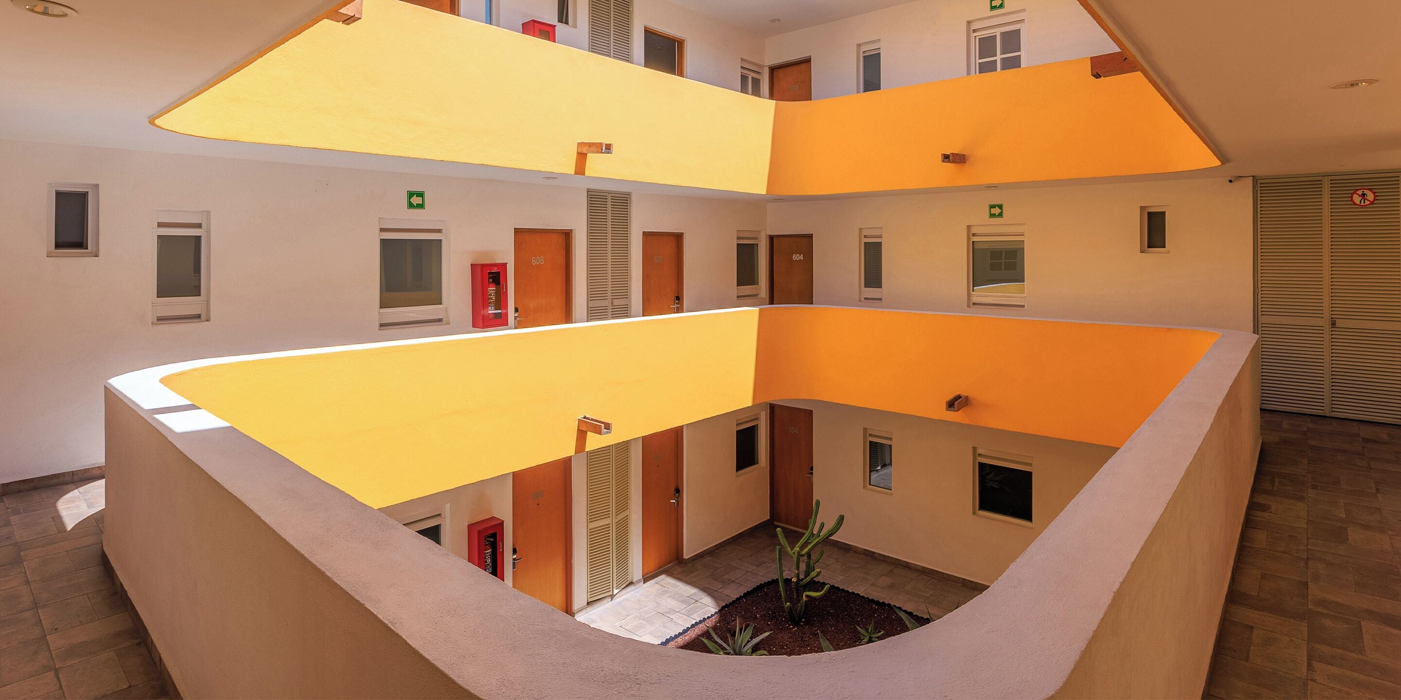 A multi-level atrium with a central courtyard, featuring a staircase, multiple doors, and a small plant arrangement.