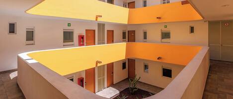 A multi-level atrium with a central courtyard, featuring a staircase, multiple doors, and a small plant arrangement.