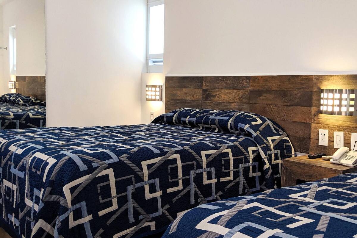 A hotel room with two beds, a wooden headboard, bedside lamps, a phone, and a mirror.