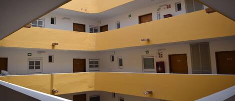 A multi-level building with yellow and white walls, multiple doors, and windows.