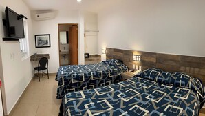 A hotel room with two beds, a TV mounted on the wall, a bathroom with a sink, and a chair. - Opportunity León (León)