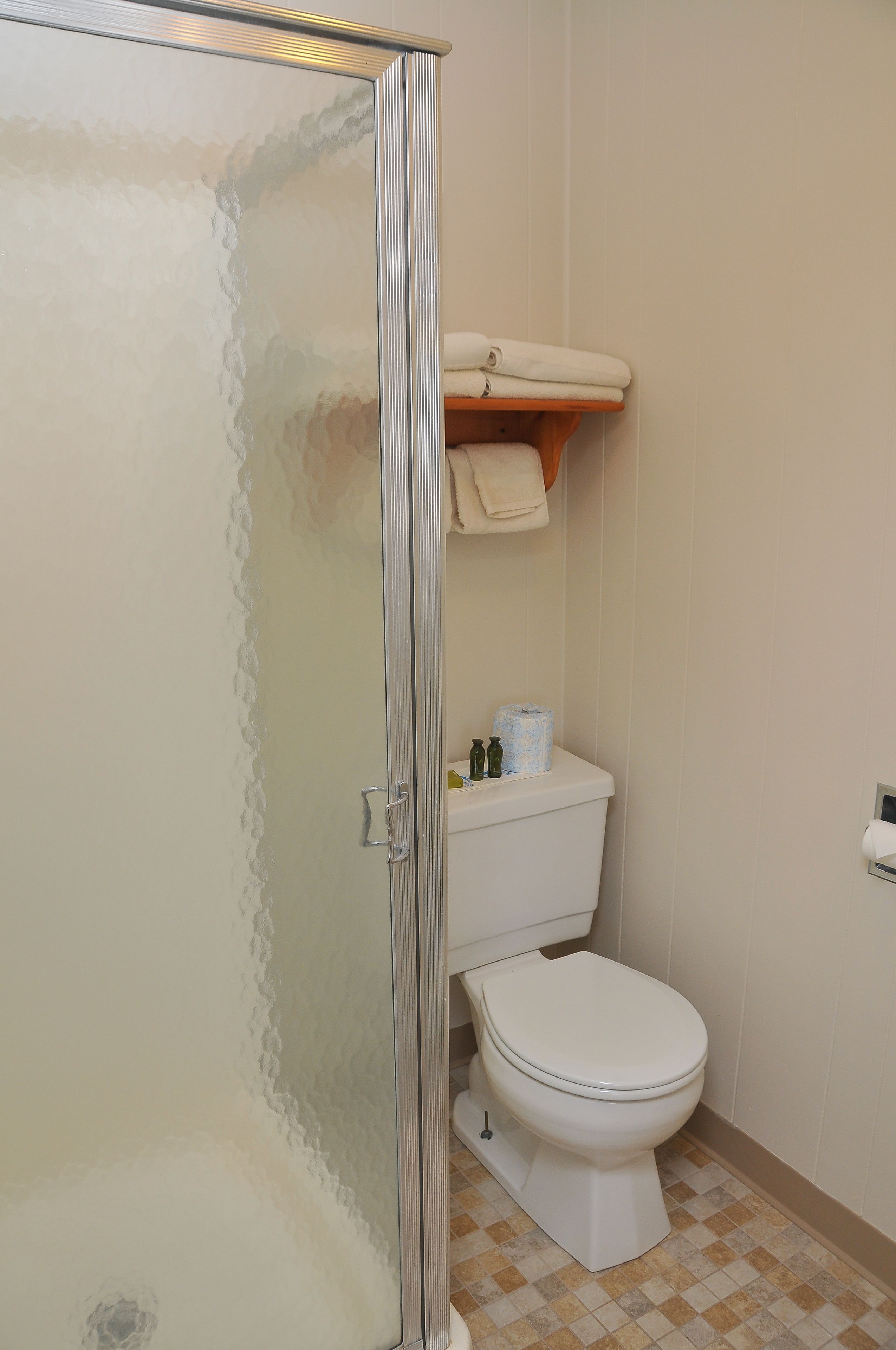 Ein Badezimmer mit Duschkabine aus Glas, Toilette und Ablagefläche mit Handtüchern.